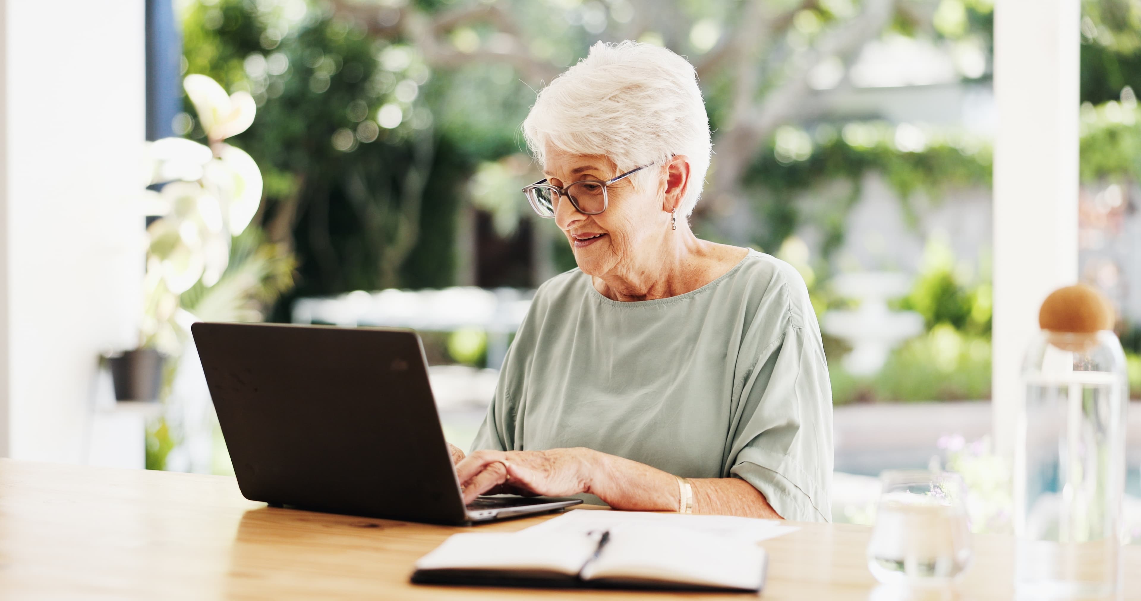Oudere cursist volgt thuis een online taaltraining achter een laptop