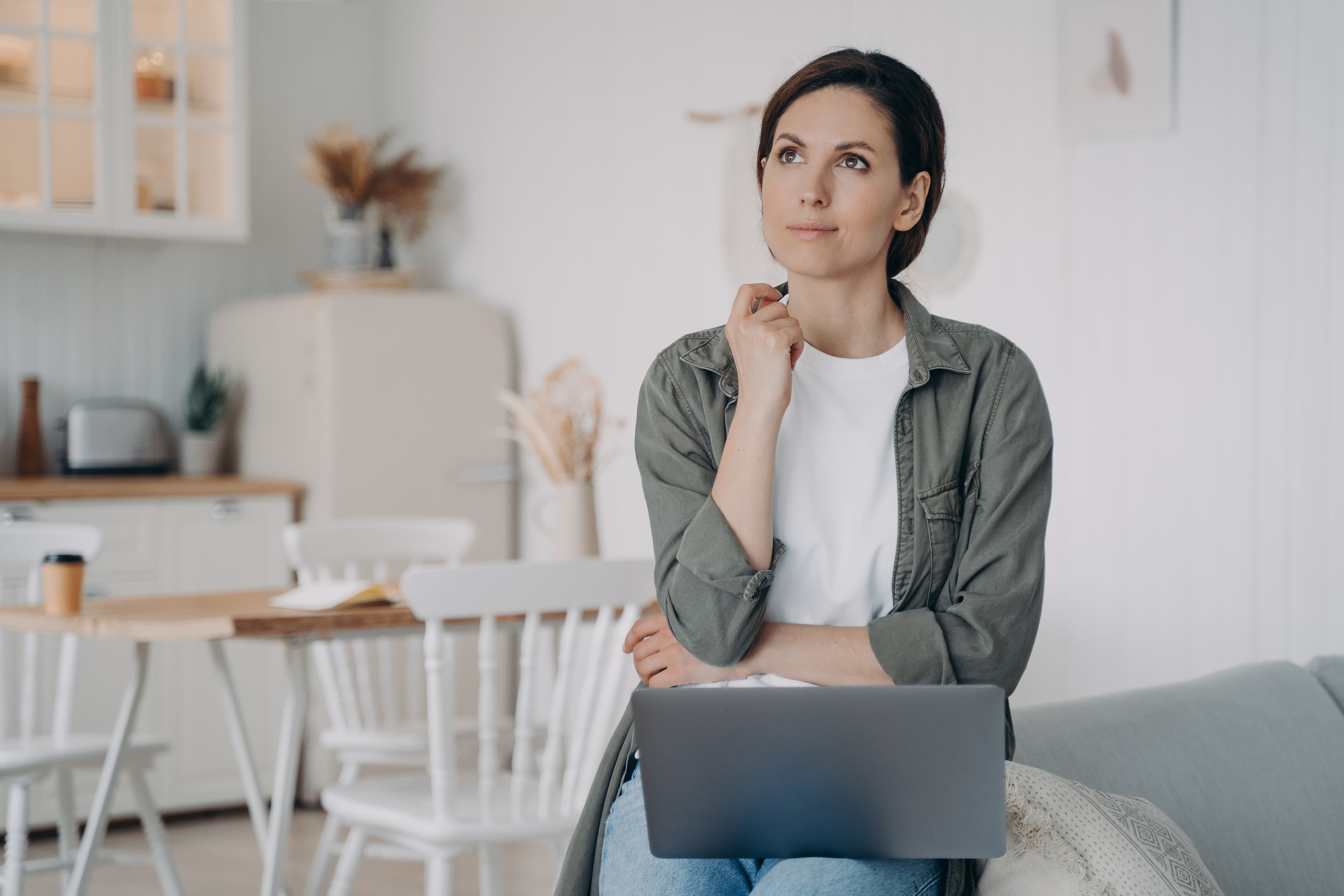 Vrouw denkt na met laptop op schoot